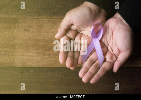 Hand mit Lavendel Band auf Holztisch. symbol für alle Krebs Konzept Stockfoto