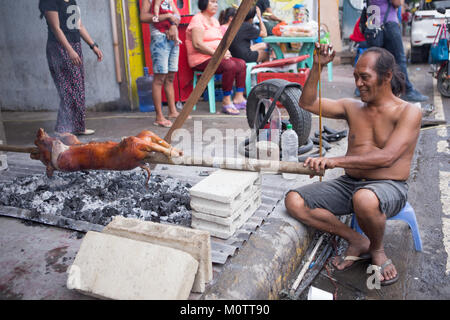 Ein Mann ein Schwein am Spieß braten wie Lechon Baboy in den Philippinen bekannt. Als nationale Lieblingsgericht betrachtet. Stockfoto