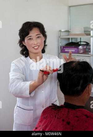 Lächelnd Nordkoreanischen friseur Haare schneiden, Süd-pyongan Provinz, Chongsan-ri Kooperative Farm, Nordkorea Stockfoto