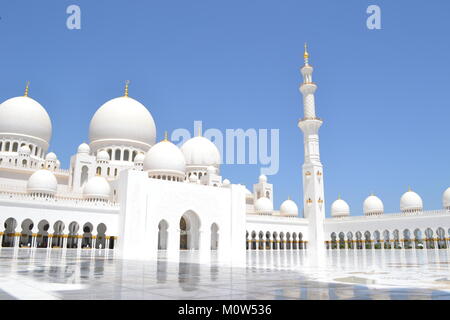 Die wunderschöne, unberührte weiße Sheikh Zayed Moschee mit Minaretten und Kuppeln, Säulen, von innen, mit dem strahlend blauen Himmel im Hintergrund. Stockfoto