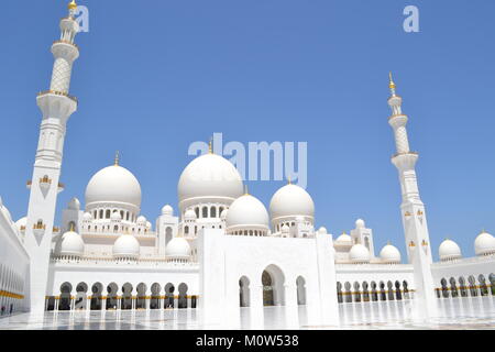 Die wunderschöne, unberührte weiße Sheikh Zayed Moschee mit Minaretten und Kuppeln, Säulen, von innen, mit dem strahlend blauen Himmel im Hintergrund. Stockfoto