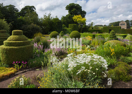 Formgehölze und bunten Blumenrabatten der Blume Garten mit Gartenhaus im Hintergrund, Herterton House Gardens, Northumberland, England Stockfoto