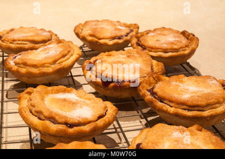 Frisch zubereitete hausgemachte Torten Gehacktes, heiß aus dem Ofen und Abkühlen am Draht Rack, mit einer Prise Zucker. Ein traditionelles Weihnachtsessen behandeln. Stockfoto