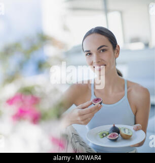 Porträt Lächeln brünette Frau essen, Feigen und Kiwis Stockfoto