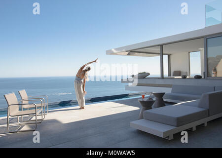 Frau Yoga seitliche Streckung auf moderne, luxuriöse Home Showcase äußere Terrasse mit Meerblick Stockfoto
