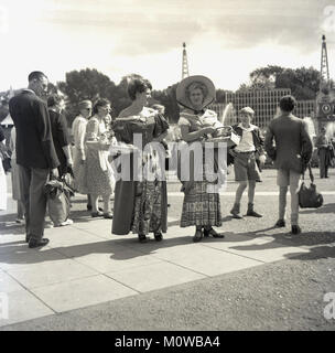 1951, historisches Bild vom Festival von Großbritannien feiern auf dem Festival Lustgärten, Battersea Park, London, England. Bild zeigt zwei Damen im Kostüm, weidenkörbe Obst unter den Besucher. Eines der Ziele des Festivals war die Förderung und Feier der Britischen Ideen, Kultur, Kunst und Kunsthandwerk und Lebensmittel als Hilfe für die nationalen Aufschwung in der harten Nachkriegszeit. Stockfoto