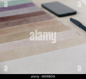 Helle Sammlung von bunten Textilproben mit Wildleder Textur. Mockup mit Stoffmuster, Smartphone und schwarzen Mappe. Stockfoto