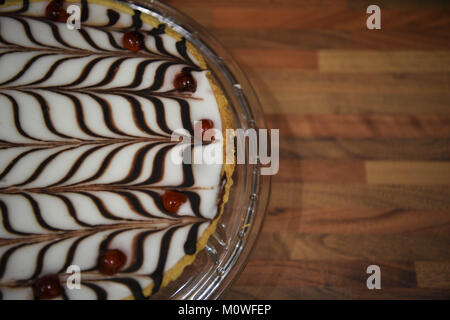 Essen Fotografie von einem hausgemachten Bakewell tart Kuchen mit kurzen Kruste Gebäck frangipane und Mandeln mit einem Muster iced Topping Schokolade und Kirschen Stockfoto