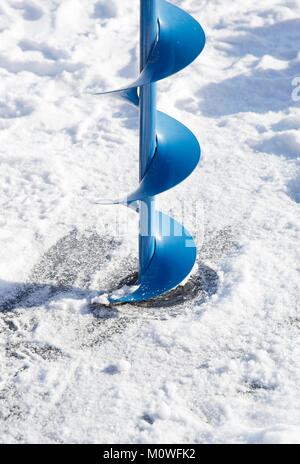 Ein eis Schnecke (eine spiralförmige Schraube Blade) Anfang ein Loch in das Eis auf einem zugefrorenen See zum Eisfischen zu bohren. Stockfoto