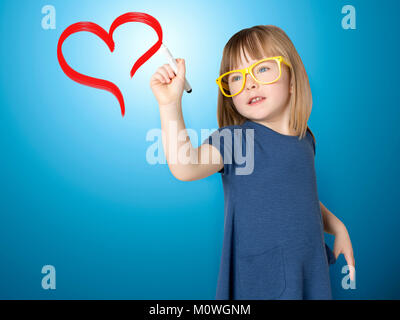 Süße kleine Mädchen in gelbe Brille zeichnet Rotes Herz. Stockfoto