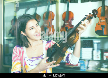 Junge Mädchen die Wahl der klassischen Violine in der Musik instrumente Studio Stockfoto