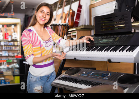 Fröhlich lächelnd langhaarige Mädchen Wahl synthesizer music shop Stockfoto