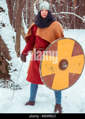 Fränkischer Krieger im historischen Kostüm mit Schwert, Schild, Helm im Winter Wald Stockfoto