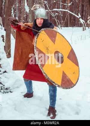 Fränkischer Krieger im historischen Kostüm mit Schwert, Schild, Helm im Winter Wald Stockfoto