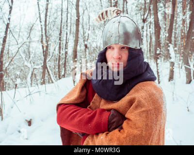 Fränkischer Krieger im historischen Kostüm mit Helm im Winter Wald Stockfoto