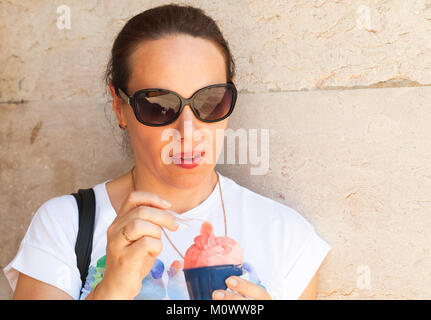 Europäischen jungen erwachsenen Frau isst rosa Fruchteis, close-up Outdoor Portrait Stockfoto