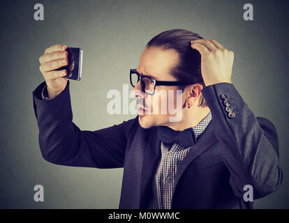 Junger Mann unter Haarverlust leiden, an der Reflexion. Stockfoto