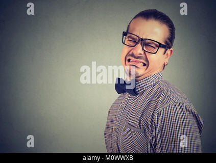 Mann in Brillen und formelle Kleidung Grimasse mit Abscheu auf grauem Hintergrund. Stockfoto