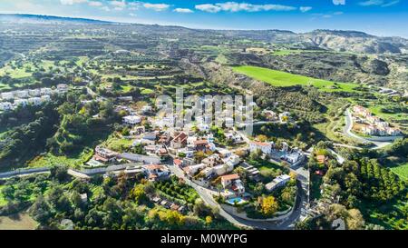 Antenne Blick aus der Vogelperspektive Goudi Dorf in Polis Chrysochous Tal, Paphos, Zypern. Blick auf traditionelle keramische Fliesen Dach Häuser, Kirche, Bäume, Hügel Stockfoto