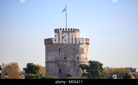 Der weiße Turm von Thessaloniki, Griechenland unter strahlend blauem Himmel, umgeben von Bäumen. Stockfoto