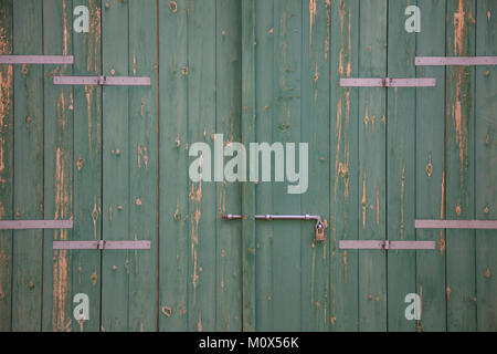 Holz- grüne Tür. Verwitterte leer, Banner, Hintergrund mit rostiger Riegel und Vorhängeschloss. Nahaufnahme, Detail Stockfoto