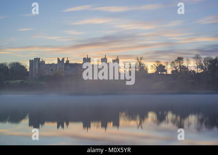 Framlingham Schloss in Suffolk bei Sonnenaufgang auf dem Wasser spiegelt Stockfoto