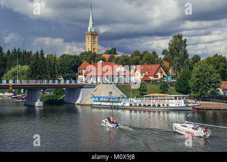 Blick von der Fußgängerbrücke in Mikolajki Talty See in der Woiwodschaft Pommern in Polen. Evangelische Kirche der Heiligen Dreifaltigkeit auf Hintergrund Stockfoto