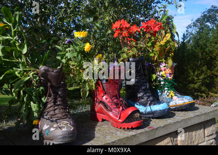 Alten bunten Schuhe recycelt in Pflanzmaschinen auf einer Wand an, RHS Garden Harlow Carr, Harrogate, Yorkshire. UK. Stockfoto