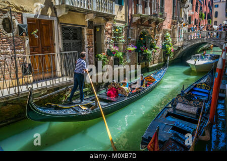 Die Gondeln tragen Touristen auf dem Kanal vom 3. Juli 2017, Venedig, Italien. Enge Kanäle, historische Gebäude und Reflexion auf dem Wasser. Stockfoto