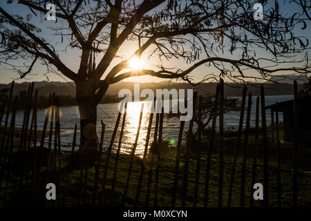 Sonnenuntergang über Bahia de Miel mit Baum und Zaun Silhouette in Baracoa, Kuba Stockfoto