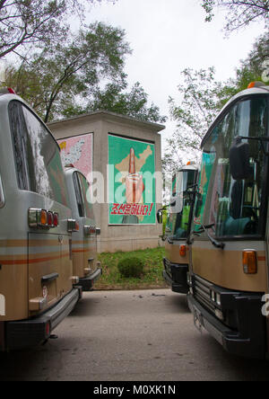 Nordkoreanische Busse für Touristen mit der Wiedervereinigung Poster im Hintergrund geparkt auf die Entmilitarisierte Zone,Hwanghae Province, Panmunjom, Nordkorea Stockfoto