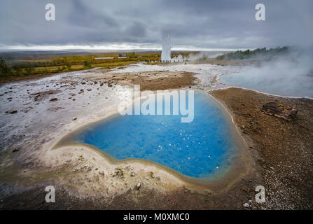 Geothermische Hot Spring mit Strokkur Geysir im Hintergrund ausbrechenden, Island Stockfoto