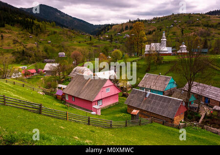 Synevyrs'ka Poliana Dorf in den Karpaten. schöne ländliche Landschaft mit Holzzäunen auf grashängen und eine Kirche auf einem Hügel zwischen den Häusern. beautifu Stockfoto