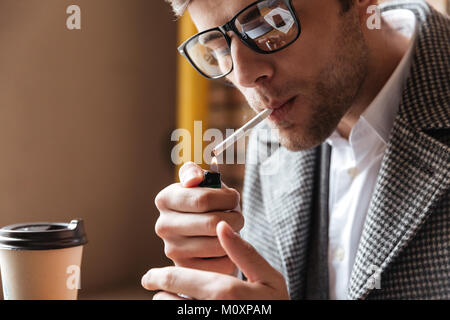 Schließen Sie herauf Bild des Geschäfts Mann in Brillen saßen am Tisch im Cafe und Rauchen Zigarette Stockfoto