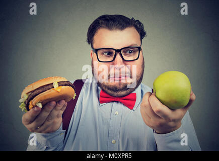 Übergewichtigen Mann, Hamburger und green apple Probleme mit Diät Wahl. Stockfoto