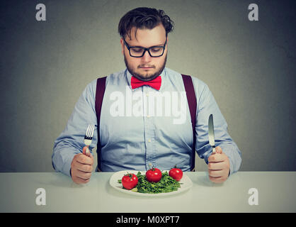 Junge übergewichtige Menschen auf gesunde Salate, die versuchen, Gewicht zu verlieren, konzentriert. Stockfoto