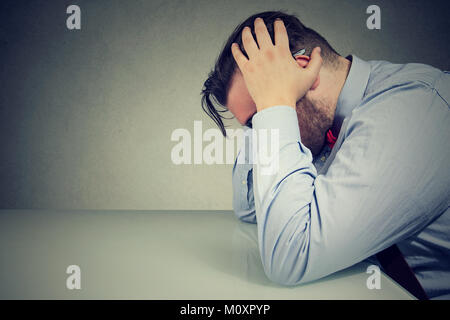 Seitenansicht des erschöpft Mitarbeiter am Tisch sitzen in totale Depression. Stockfoto