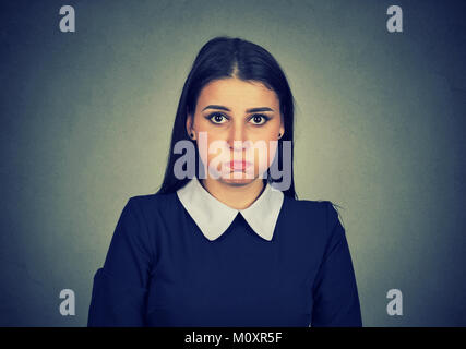 Junge Frau puffing Wangen und leider auf Kamera auf Grau posieren. Stockfoto