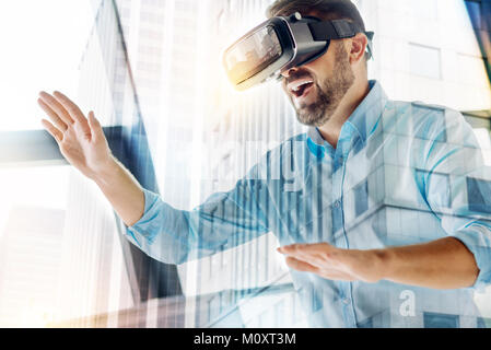 Amüsiert Mann mit virtuellen Maske mit Händen hielt Vorwärts Stockfoto