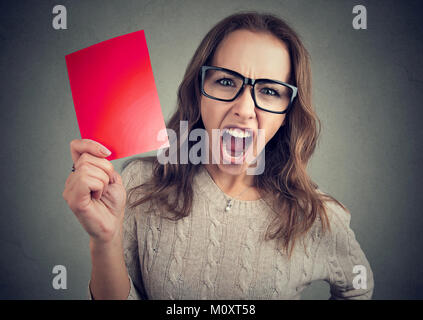 Junge Frau in Brillen mit roten Papier und wütend schreiend auf Kamera auf Grau. Stockfoto