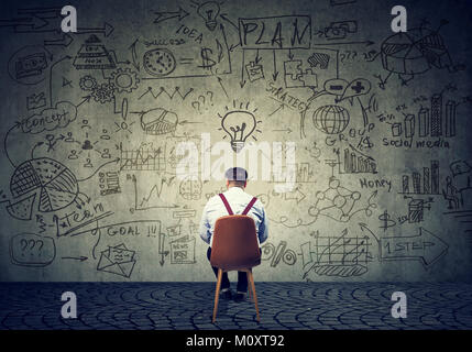 Rückansicht des chunky Mann sitzt vor der Wand mit Strategie und Plan erstellen. Stockfoto