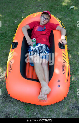 Teenager Testen seiner neuen 'Intex Explorer 200' floß vor dem Betreten des Wasser mit einer Dose "Canada Dry Ginger Ale'. Clitherall Minnesota MN USA Stockfoto