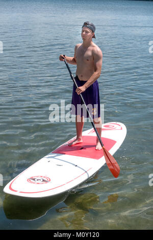 Teenager Navigation seine paddleboard auf dem See an einem schönen Sommertag. Clitherall Minnesota MN USA Stockfoto