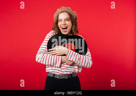 Portrait eines glücklichen Frau mit beret Holding vinyl platten über rosa Hintergrund isoliert Stockfoto