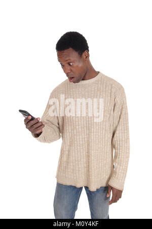 Eine schöne afrikanische amerikanische Mann in einem beige Pullover an seinem Handy in Schock suchen, auf weißem Hintergrund Stockfoto