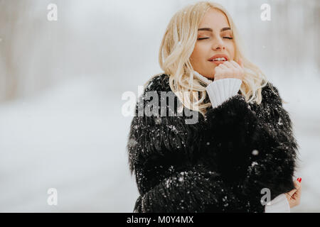 Portrait von blonde Frau draußen im Schnee Winter Mantel Stockfoto