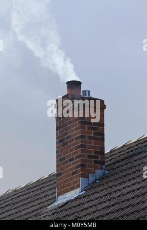 Schornstein auf die inländischen Haus mit wehenden weißen Rauch aus dem Schornstein pot Stockfoto