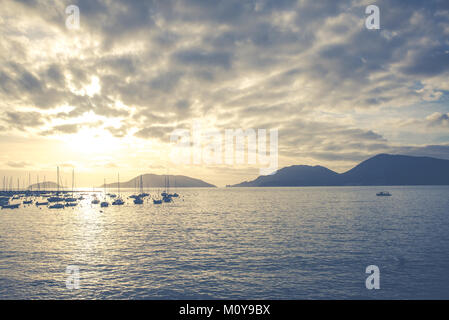 Ruhe mediterranen italienischen Meerblick von kleinen Hafen mit mehreren Booten, in der Ferne und die Berge im Hintergrund bei Sonnenuntergang. Vintage Retro, matt Stockfoto