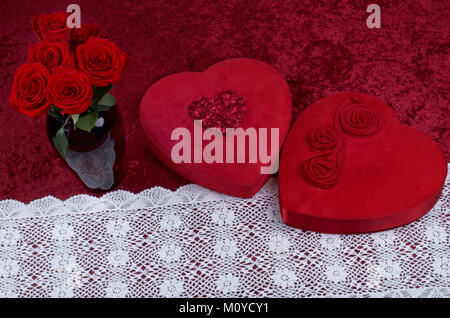 Valentine Hintergrund, rote Leathered Herz geformten Süßigkeiten, mit frischen Rote Rose Bouquet auf rotem Hintergrund, Stockfoto