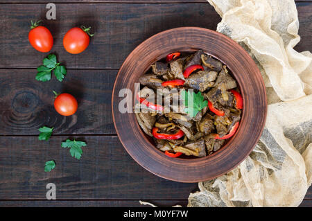 Warmer Salat von Leber und Paprika in einem Ton Schüssel auf einem dunklen Holztisch. Gebratene Leber. Die Ansicht von oben Stockfoto